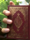 Red holly quran mushaf suriah in right hand