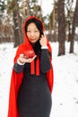 Red Hooded Woman Holding an Apple Fairytale Portrait in winter forest. Royalty Free Stock Photo