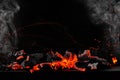 Hot burning coals on barbecue tray on black background with sparks and white smoke Royalty Free Stock Photo