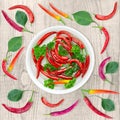 Red hot chili pepper and parsley are in a dish with water. Top view, wooden square background Royalty Free Stock Photo