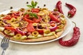 Red hot chili pepper on white surface close up. On blurred background vegetarian pizza with tomatoes, bell pepper, onion Royalty Free Stock Photo