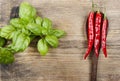 Red hot chili peppers and basil leaves on wood Royalty Free Stock Photo