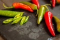 Red hot chili peppers on black board with copy space. Heap of red and green pepper. Bright natural background.