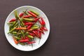 Red Hot Chili Peppers On Black and Dark Modern Background or Black Table, on a Round Plate. A Lot of Red Chilli Peppers. Green Hot Royalty Free Stock Photo