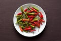 Red Hot Chili Peppers On Black and Dark Modern Background or Black Table, on a Round Plate. A Lot of Red Chilli Peppers. Green Hot Royalty Free Stock Photo