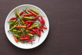 Red Hot Chili Peppers On Black and Dark Modern Background or Black Table, on a Round Plate. A Lot of Red Chilli Peppers. Green Hot Royalty Free Stock Photo