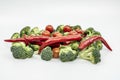 Red hot chili peppers, ripe cherry tomatoes and raw broccoli stalks on a plain white surface Royalty Free Stock Photo