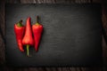 Red hot chili peppers on a slate board on a dark wooden table. Top down overhead view