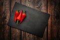 Red hot chili peppers on a slate board on a dark wooden table. Top down overhead view