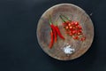 Red hot chili peppers and sliced peppers on a wooden craft old cutting board with salt crystals nearby