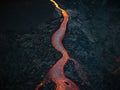 Red hot lava flow streaming over black volcanic rocks, aerial directly above Royalty Free Stock Photo