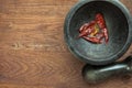 Red hot pepper in a stone granite mortar, dried chillies crunched top view on wooden background copy space Royalty Free Stock Photo