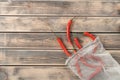 Red hot tasty chili peppers in ecological degradable string bag on wooden background. Spicy food seasoning and condiment