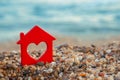 Red house with heart, lovely house from the sea. Symbol of house on gravel near the ocean Royalty Free Stock Photo