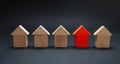 Red house model among wooden houses, black color background