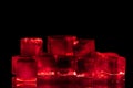 Red ice cubes on black background  closeup, transparent frozen burgundy wine color water with red backlight and reflection Royalty Free Stock Photo