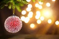 Red with ice pimples Christmas ball on a live branch of a fir tree with Golden lights of garlands in defocus. New year, Christmas Royalty Free Stock Photo