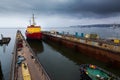 Red icebreaker docked in shipyard floating dry dock for repair, under cloudy sky. Maritime industrial marine vessel Royalty Free Stock Photo