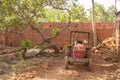 Red indian tractor with hindcarriage near green tree on the background of a stone wall Royalty Free Stock Photo