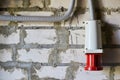 Red industrial connector for electrical appliances located on a brick wall. Royalty Free Stock Photo