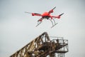 Red industrial drone flies over metal structures industrial faci