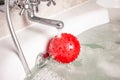 Red inflatable childrens ball lies under a stream of water in the f Royalty Free Stock Photo