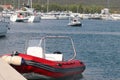 The red inflatable motor boat is moored to the pier in the background of the marina with yachts. Pilot ship to assist in the Royalty Free Stock Photo