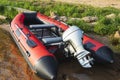 Red inflatable rubber boat with a motor near the lake shore, fishing, tourism, active recreation Royalty Free Stock Photo