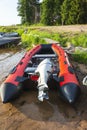 Red inflatable rubber boat with a motor near the lake shore, fishing, tourism Royalty Free Stock Photo