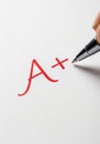 A+ Grade being written in red on papersheet. Royalty Free Stock Photo