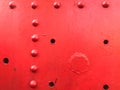 Red iron metal rough painted strong solid industrial wall with rivet holes and bolts. Background, texture Royalty Free Stock Photo