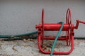 Red iron object for hose reel in field, placed on selectable focus cement floor.