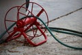 Red iron object for hose reel in field, placed on selectable focus cement floor.