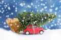Red car carrying christmas tree with snowflakes Royalty Free Stock Photo