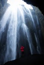 Red jacket person at Gljufrabui Gljufrafoss hidden waterfall cave canyon dweller cliff rock Seljalandsfoss South Iceland