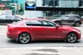 Red Jaguar XE riding on the highway. Side view of shiny compact executive car driving in the street Royalty Free Stock Photo