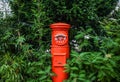 Red Japan Post mailbox surrounded by green shrubbery