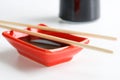 Red Japanese sauce bowl - seyuzaru, chopsticks and a bottle of soy sauce on a white kitchen table. Selective focusing. Daylight Royalty Free Stock Photo