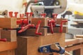 Red joiner clamps are fixed on product, gluing of boards. Bonding of wooden parts in carpentry workshop