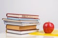 Red juicy apple lies on a yellow folder on the table, next to a stack of training books