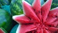 Red juicy cut watermelon in a form of flower on green blurred background. Selling farm products in a local market. Concept of food