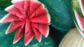 Red juicy cut watermelon in a form of flower on green blurred background. Selling farm products in a local market. Concept of food