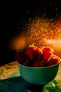 red juicy ripe strawberries in a blue vase on a black background. Drops of water, warm sunshine, back light, vertical Royalty Free Stock Photo