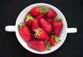 Red, juicy, ripe strawberries on a white bowl and black background Royalty Free Stock Photo