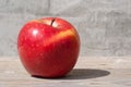 Red juicy solid fruit apple under sunlight on a blackboard against a gray wall. Concept of a natural organic healthy food