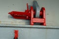 Red jumping stopper or securing cleat with chain used to secure movement of hatch covers of container ship while vessel is at sea.