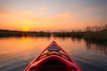A red kayak is in the water with the sun setting in the background Royalty Free Stock Photo