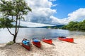 Red kayaks on a sandy beach in the summer in Loch Lomond, Scotland