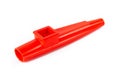 Red kazoo, plastic traditional musical instrument object isolated on white, cut out, closeup. Kids wind instruments with vibrating