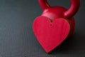 Red kettlebell on a black gym floor with large red heart